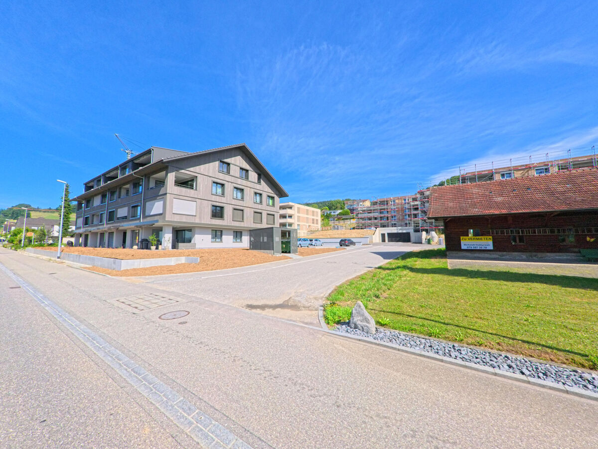 In Dagmersellen (6253, Kanton Luzern) stehen ein modernes Wohnhaus und ein traditionelles Gebaeude mit Mietangebot nebeneinander, waehrend im Hintergrund ein Neubaugebiet im Bau ist.