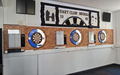Im Spiellokal des Dart Club Brugg in Brugg (5200, Kanton Aargau) sind drei Dartscheiben mit elektronischen Anzeigen an einer beleuchteten Wand montiert.