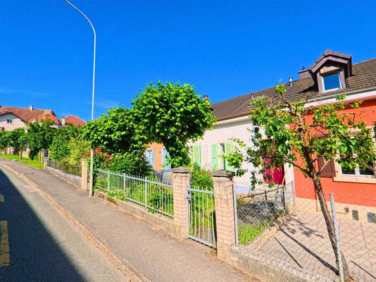 In einem Wohnquartier von Delémont (2800, Kanton Jura) stehen farbige Einfamilienhäuser mit kleinen Vorgärten entlang einer ruhigen Strasse.
