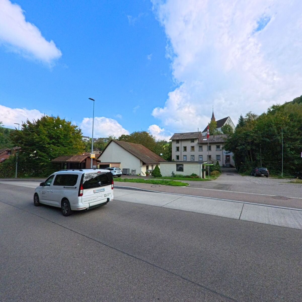 Im Zentrum von Densbüren (5026, Kanton Aargau) steht das Gemeindehaus mit Turm und Schweizer Flagge, umgeben von Wohnhäusern und Bäumen.
