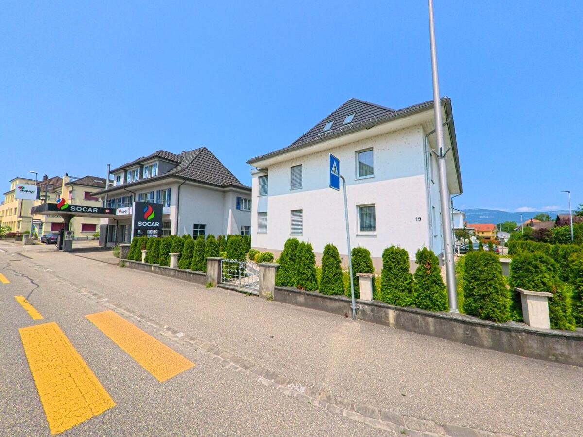 In Derendingen (4552, Kanton Solothurn) verläuft eine Strasse mit Fussgängerstreifen entlang eines Wohnhauses und einer SOCAR-Tankstelle mit moderner Architektur.