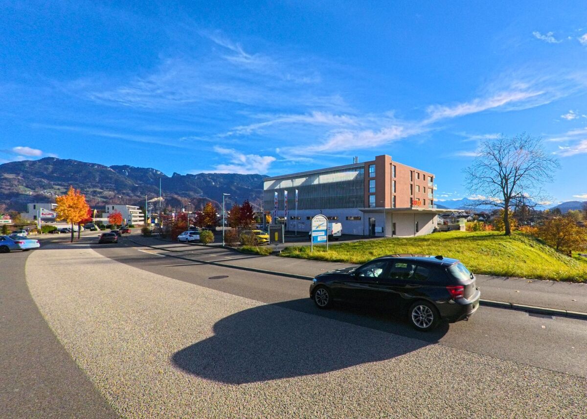 In Diepoldsau (9444, Kanton St. Gallen) steht ein modernes Gebaeude auf einer kleinen Anhöhe, umgeben von Parkflaechen, herbstlichen Baeumen und dem Alpenpanorama.