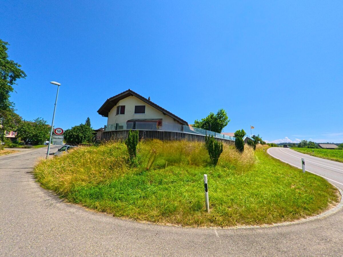 Am Ortseingang von Diessbach bei Büren (3264, Kanton Bern) verzweigen sich zwei Straßen an einer begrünten Verkehrsinsel mit Geschwindigkeitsbegrenzungsschild.