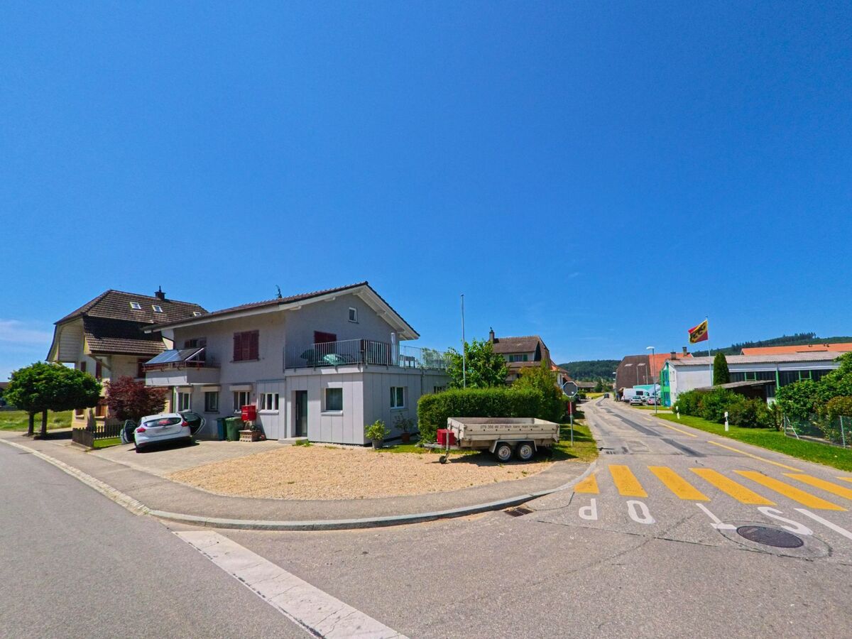 In Diessbach bei Büren (3264, Kanton Bern) markiert ein gelbes Stoppsignal den Übergang zwischen einem Wohnquartier und einem Gewerbegebiet mit wehender Kantonsfahne.