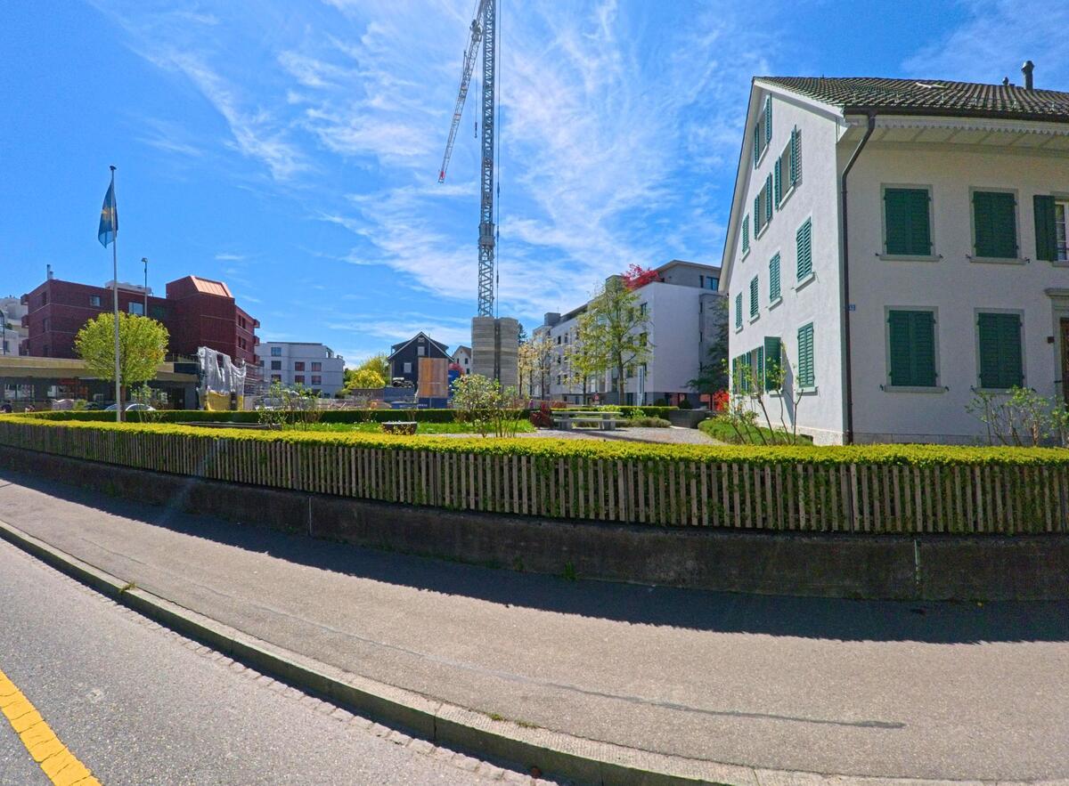 In Dietlikon, PLZ 8305 im Kanton Zürich, trifft eine Wohnstrasse auf eine zentrale Baustelle mit Kran, umgeben von Alt- und Neubauten sowie einer kleinen Grünanlage.
