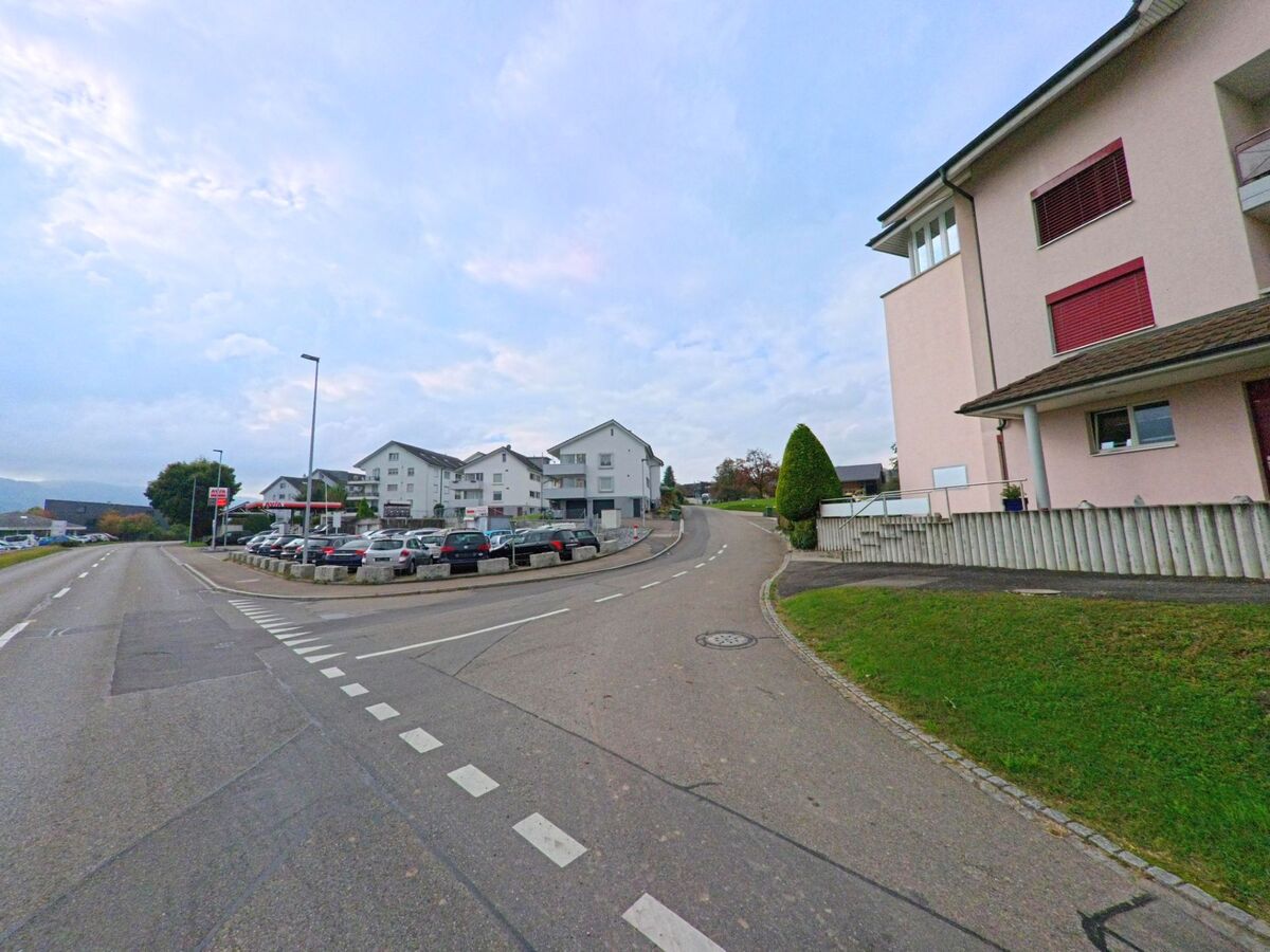 Am Ortseingang von Dietwil (6042, Kanton Aargau) reihen sich moderne Wohnbauten entlang einer breiten Strasse mit Parkplätzen und gepflegtem Umfeld.