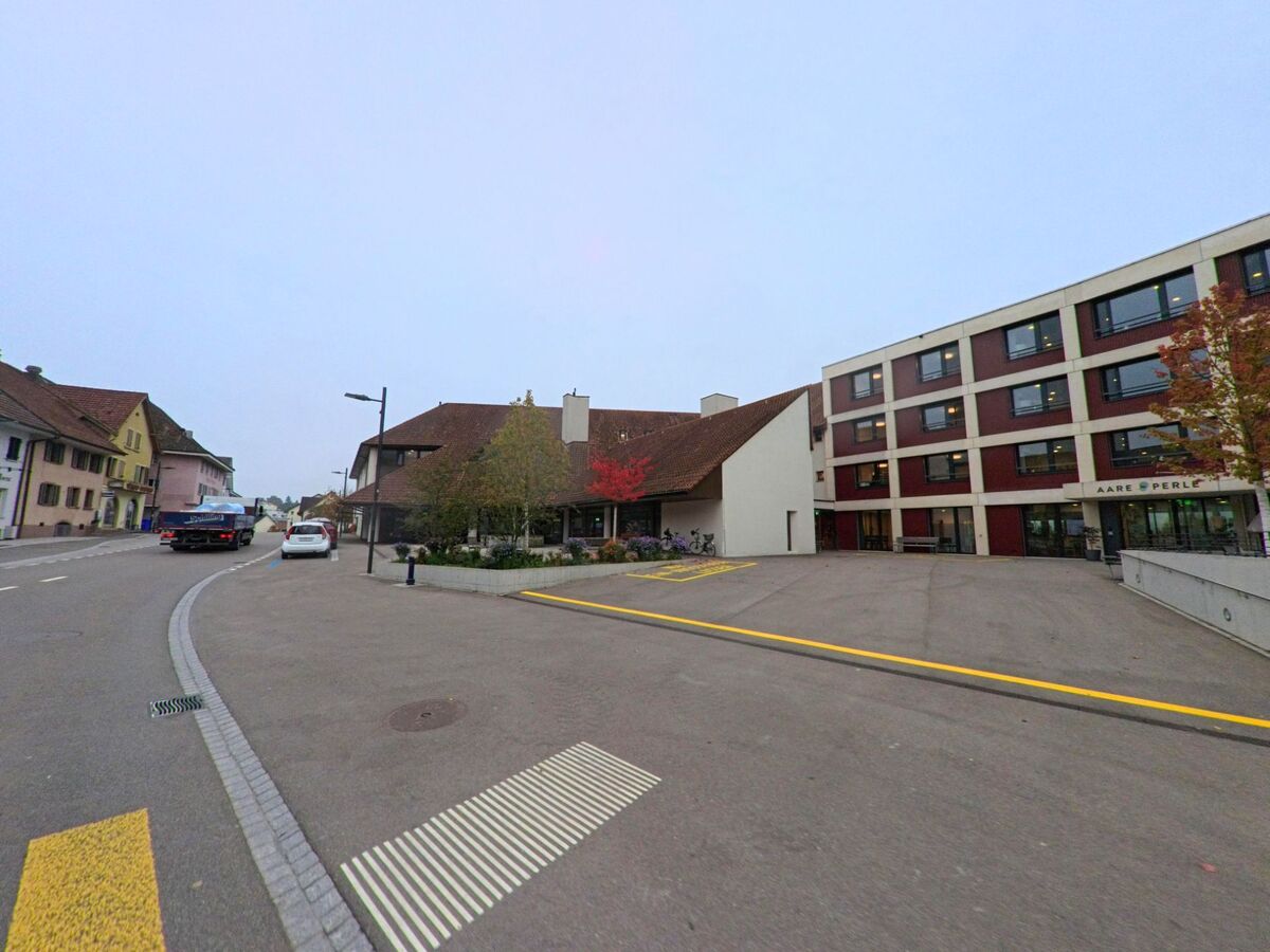 An der Hauptstrasse in Döttingen (5312, Kanton Aargau) befindet sich das Pflegezentrum Aare Perle neben traditionellen Wohnhäusern mit farbigen Fassaden.