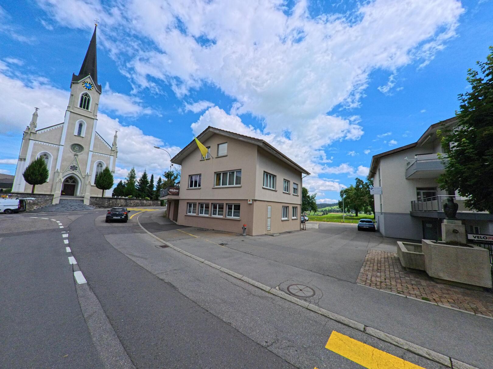 In Doppleschwand (6112, Kanton Luzern) steht die Dorfkirche leicht erhöht zwischen Wohnhäusern und Grünflächen, eingerahmt von Tannen und gepflegten Wegen.