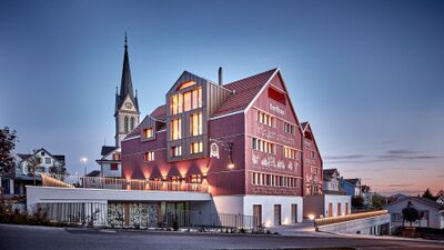 Das Dorfhus Gupf in Rehetobel (9038, Kanton Appenzell Ausserrhoden) leuchtet in der Abenddämmerung mit seiner roten Fassade und traditioneller Appenzeller Verzierung.