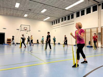 In einer Turnhalle in Horw (6048, Kanton Luzern) trainieren Mitglieder der DTV Fit-Teams Horw mit elastischen Baendern in grosszuegig verteilten Positionen.