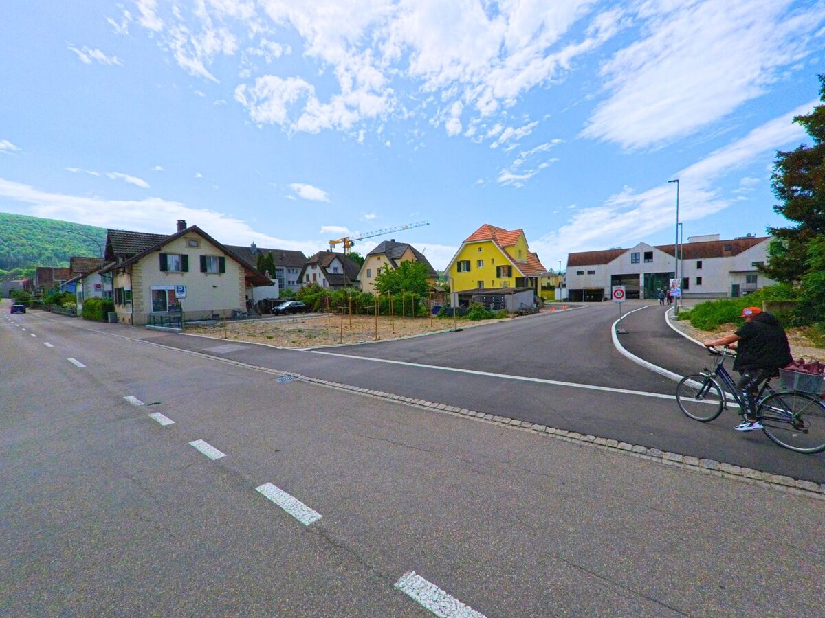 In Dulliken (4657, Kanton Solothurn) mündet eine Nebenstrasse mit Neubauten in eine Hauptstrasse, während ein Velofahrer an der Kreuzung vorbeifährt.