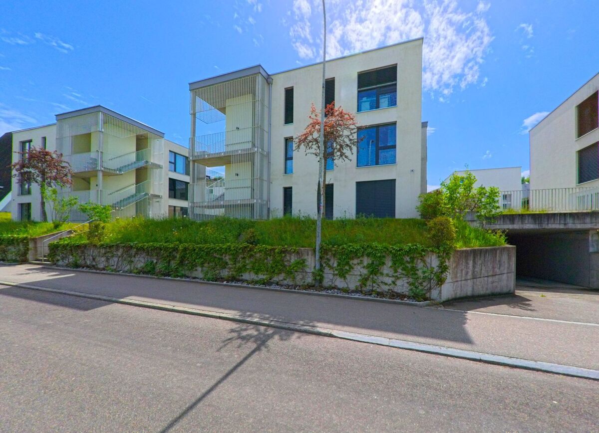  In Dulliken (4657, Kanton Solothurn) stehen moderne Wohnbauten mit offenen Treppenhäusern auf einem leicht erhöhten Grundstück mit begrüntem Vorbereich.