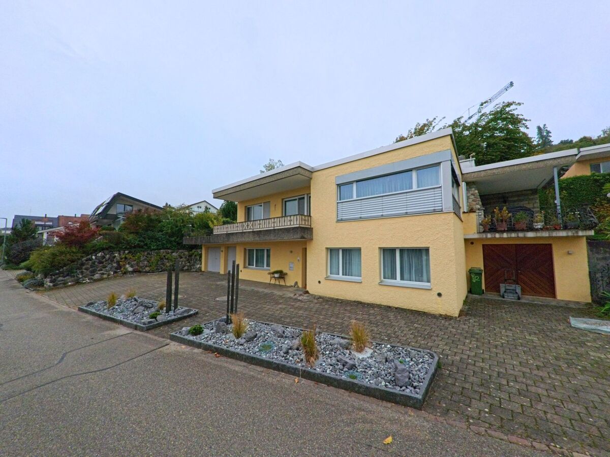 Ein hellgelbes Einfamilienhaus mit grossem Balkon und gepflastertem Vorplatz steht an einer ruhigen Quartierstrasse in Eggenwil (5445, Kanton Aargau).