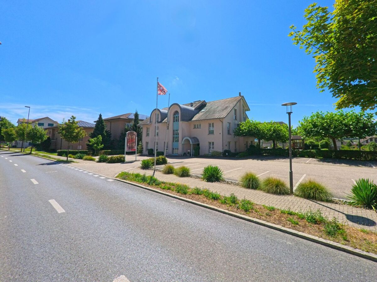 In Egolzwil (PLZ 6243, Kanton Luzern) steht ein helles Gebaeude mit Rundgiebeln und grossem Parkplatz entlang einer von Baeumen gesaeumten Hauptstrasse.