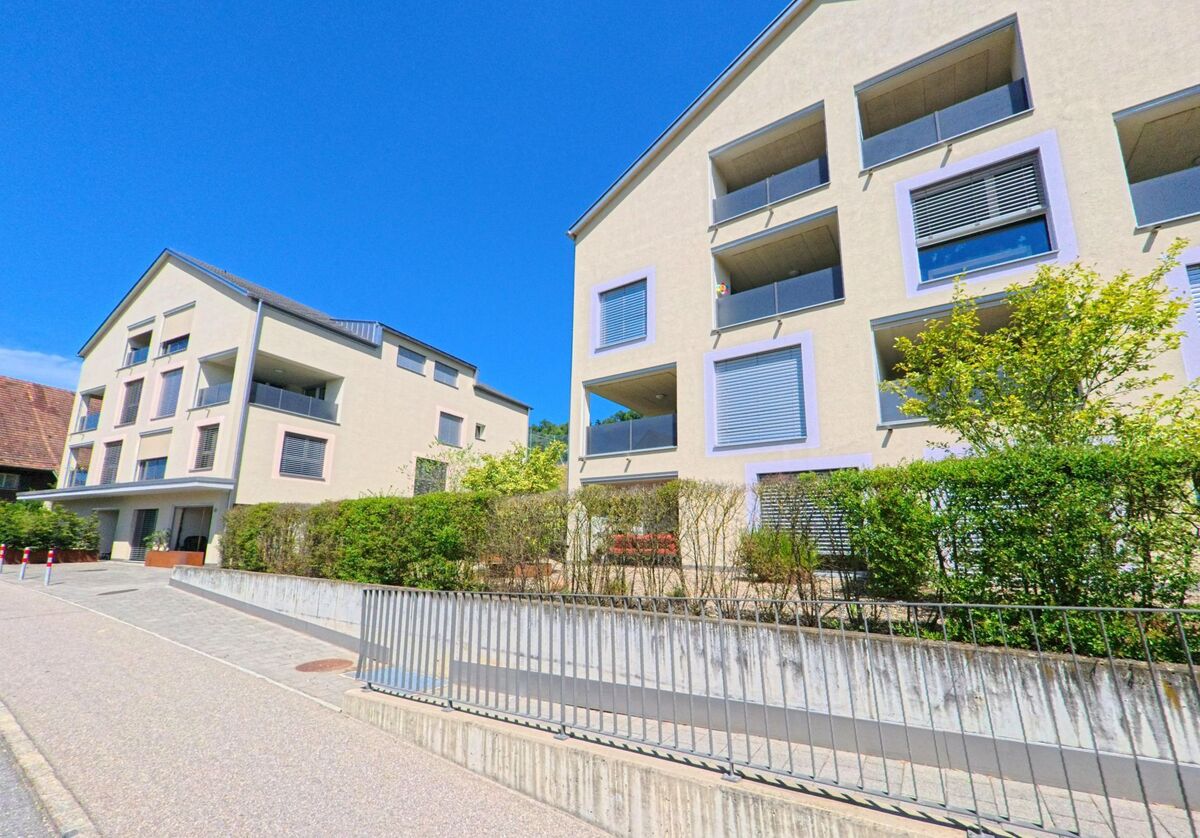 In Egolzwil (PLZ 6243, Kanton Luzern) stehen moderne Wohngebaeude mit Loggien und hellen Fassaden entlang eines leicht ansteigenden Gehwegs.