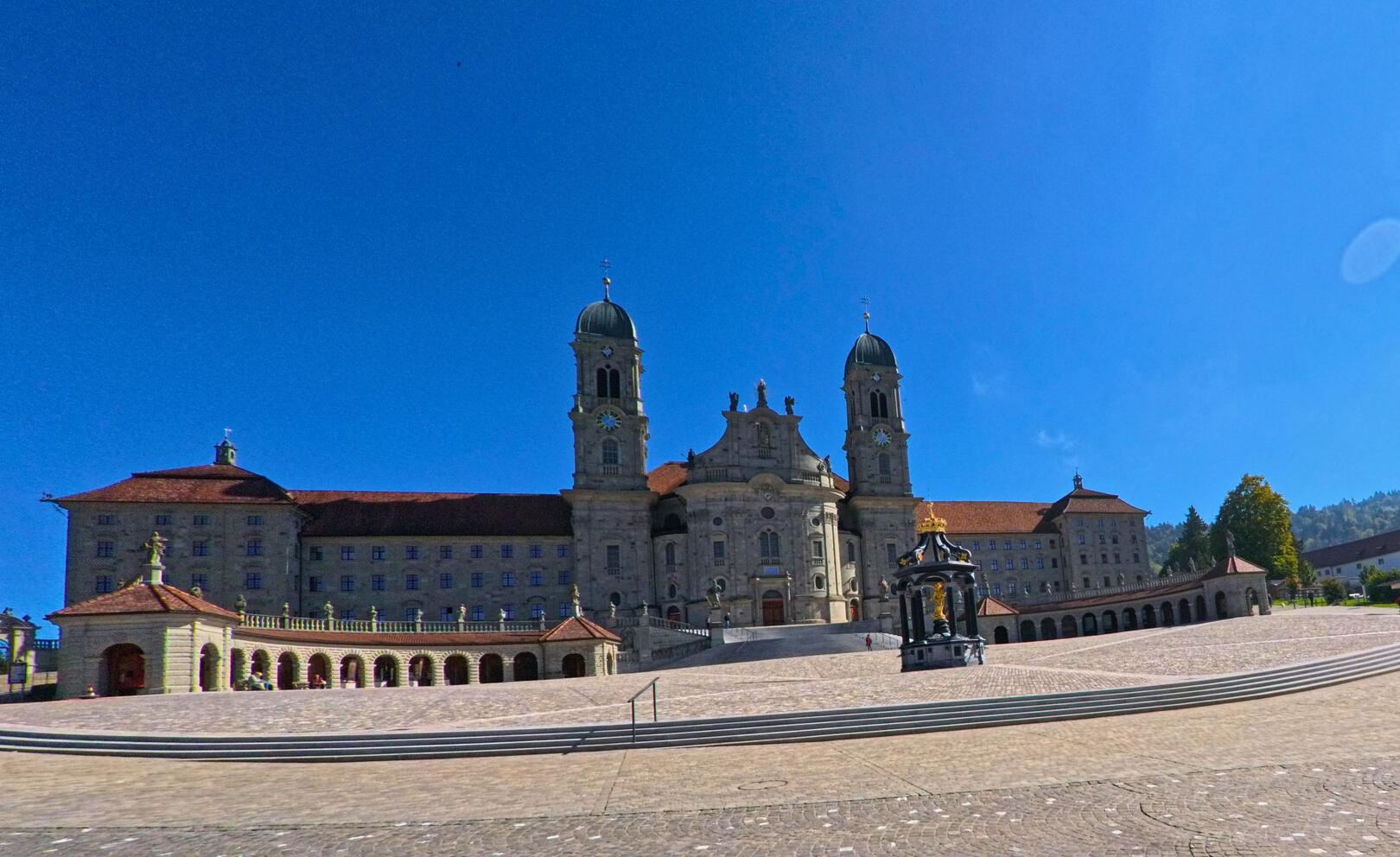 Vor dem Klosterareal in Einsiedeln (8840, Kanton Schwyz) erstreckt sich ein weitlaeufiger Platz aus Kopfsteinpflaster mit Blick auf die monumentale Fassade.