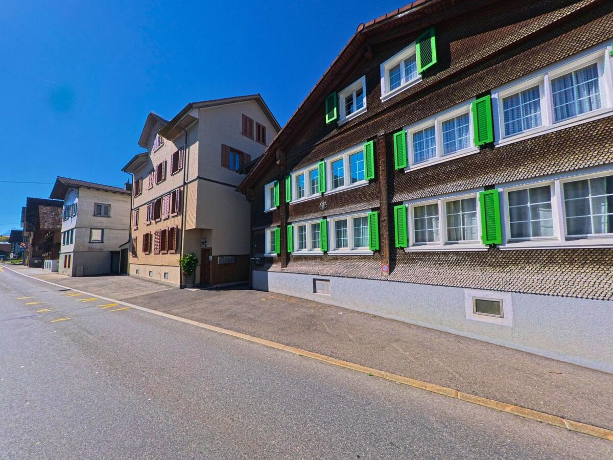 Ein traditionelles Schindelhaus mit grünen Fensterläden prägt das Ortsbild von Einsiedeln (8840, Kanton Schwyz).