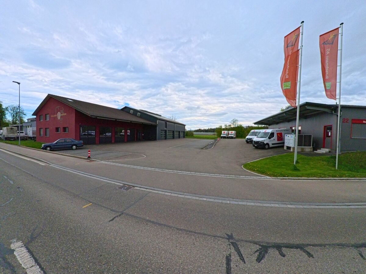 Im Industriegebiet von Ellikon an der Thur, PLZ 8548 im Kanton Zürich, befinden sich moderne Gewerbebauten mit Parkplätzen und Firmenfahrzeugen vor dem Gebäude.