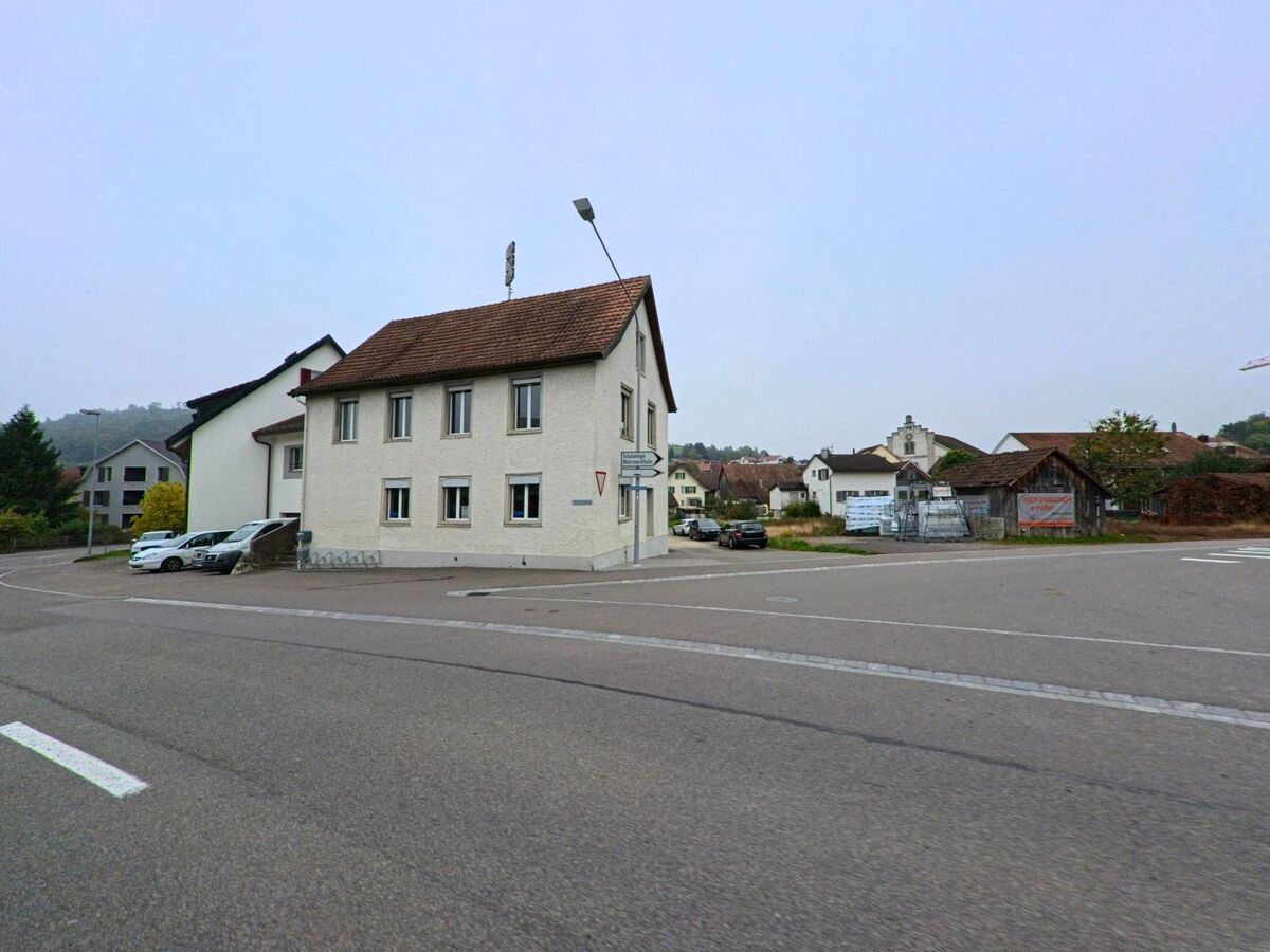 An einer Kreuzung in Endingen (5304, Kanton Aargau) steht ein zweistöckiges Wohnhaus mit Satteldach, umgeben von weiteren Gebäuden und einem kleinen Parkplatz.
