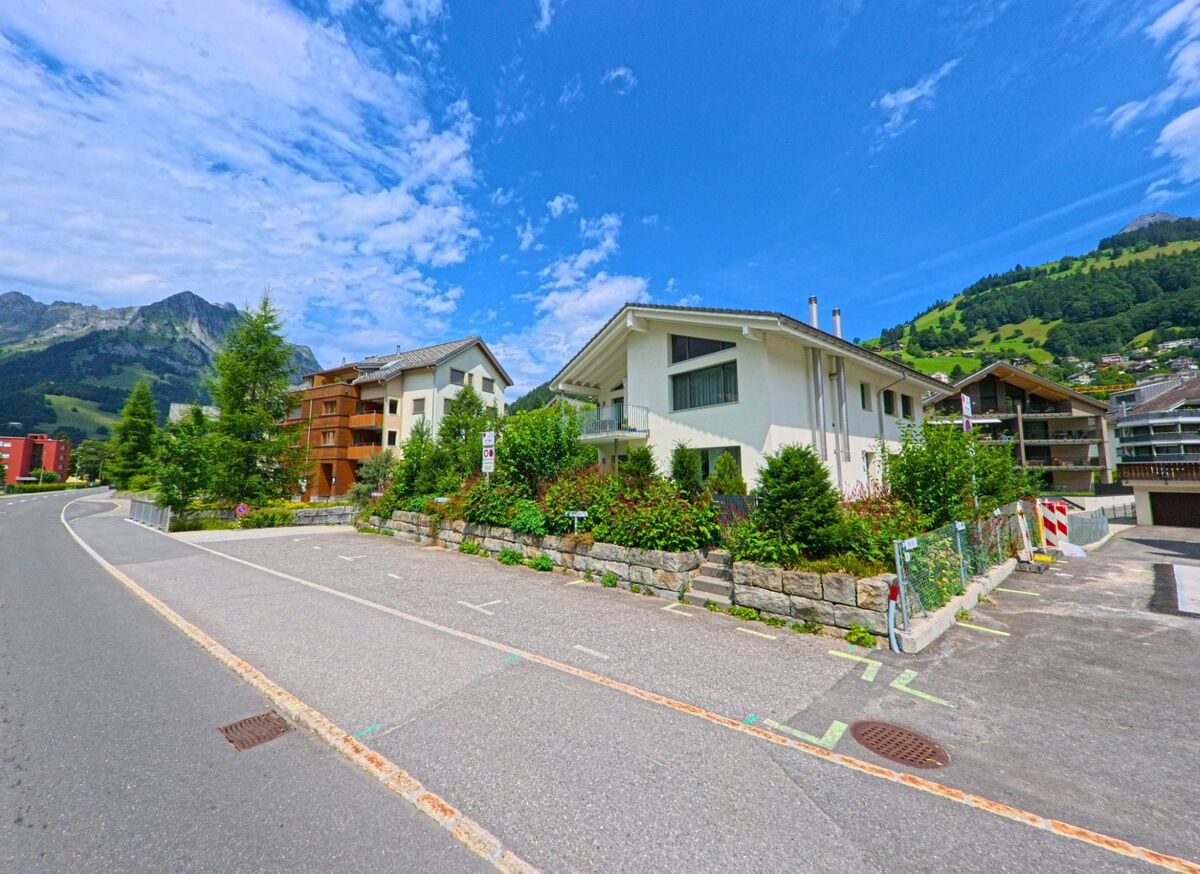 Ein Wohnquartier in Engelberg (6390, Kanton Obwalden) liegt am sanften Berghang, wo moderne Ein- und Mehrfamilienhaeuser von Gruenanlagen und Parkplaetzen umgeben sind.