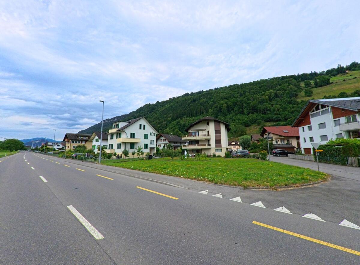 Am Fuss eines bewaldeten Hangs in Ennetbuergen (6373, Kanton Nidwalden) liegt ein Wohnquartier mit Ein- und Mehrfamilienhaeusern entlang einer breiten Ausfallstrasse.