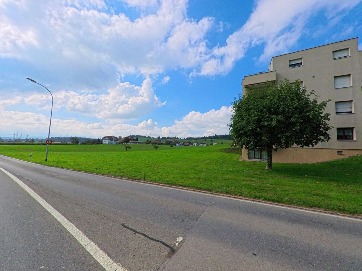 Am Ortsrand von Eschenbach (6274, Kanton Luzern) liegt ein Wohnhaus neben einer weiten grünen Wiese mit Blick auf die Hügel.