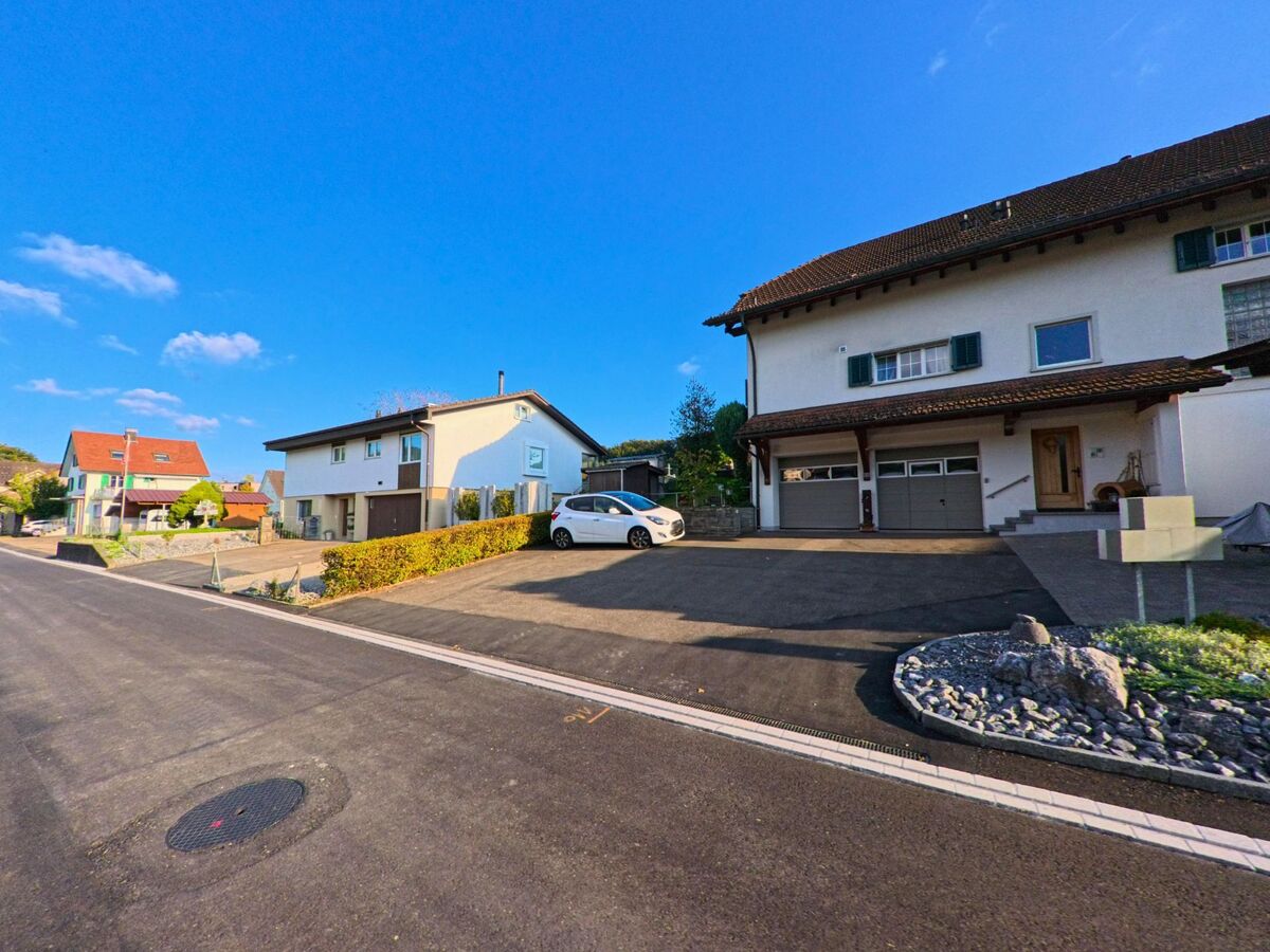 In einem Wohnquartier von Eschenbach (8735, Kanton St. Gallen) stehen gepflegte Einfamilienhaeuser mit Garagen entlang einer frisch asphaltierten Strasse.