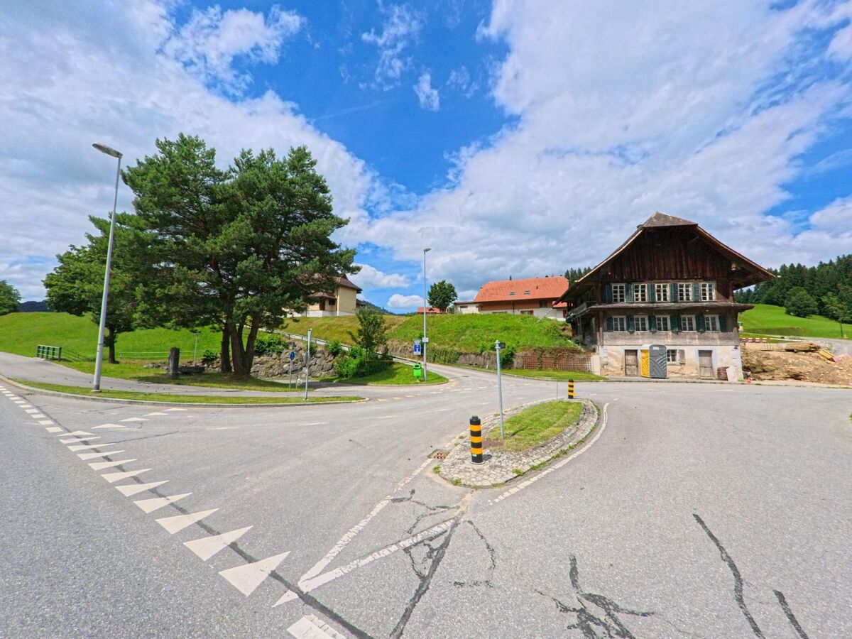 In Escholzmatt-Marbach (6182, Kanton Luzern) treffen sich mehrere Strassen an einem historischen Bauernhaus, das von Wiesen und sanften Hügeln umgeben ist.