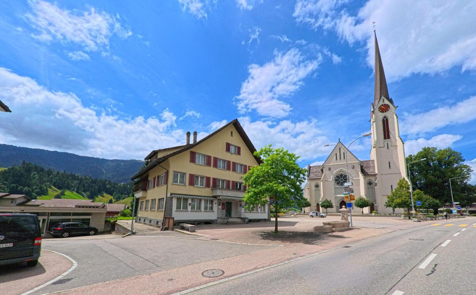 Die markante Kirche mit hohem Turm in Escholzmatt-Marbach (6182, Kanton Luzern) steht am Rand eines kleinen Platzes mit Blick auf die umliegenden Hügel.