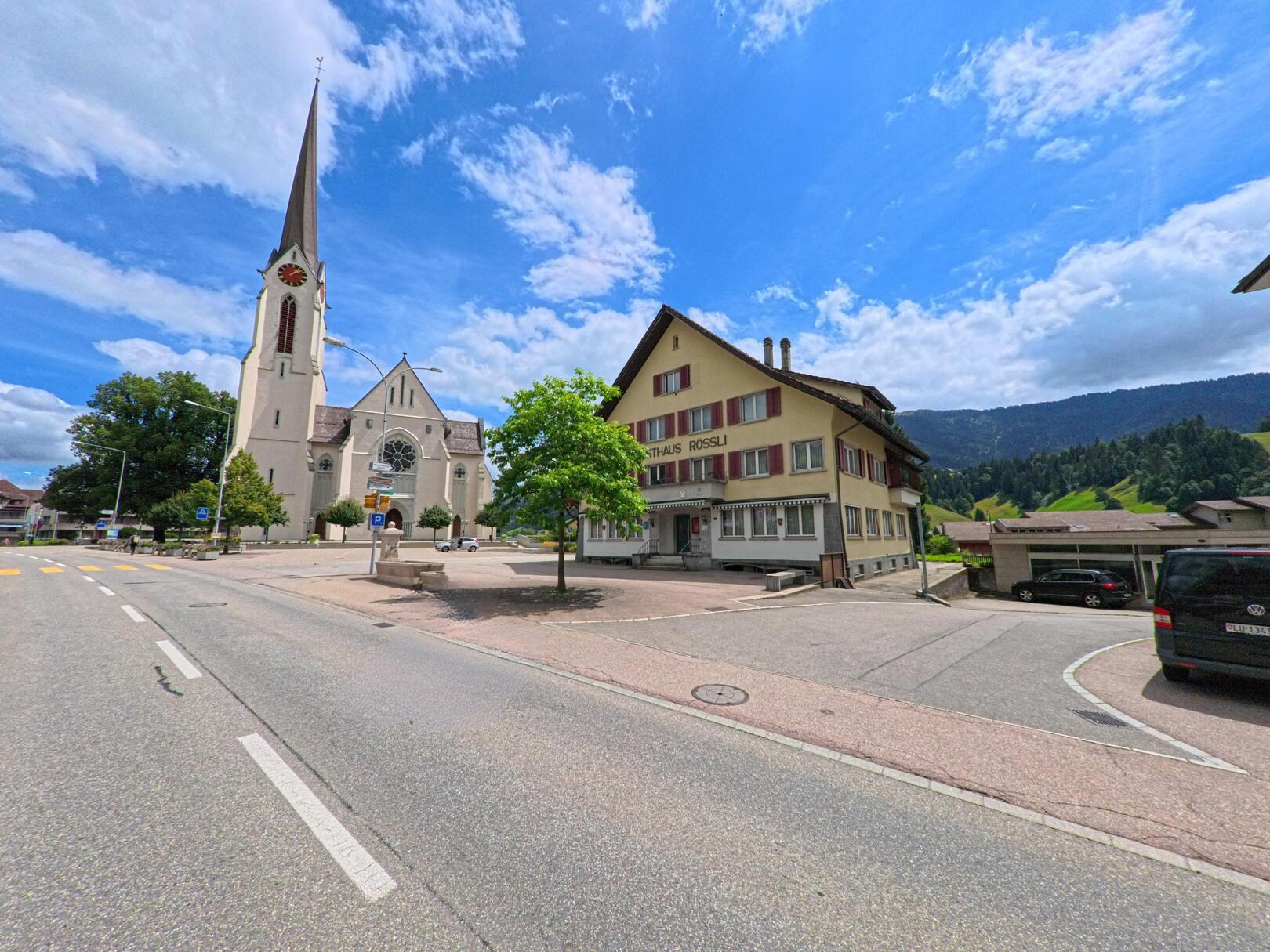 Die markante Kirche mit hohem Turm in Escholzmatt-Marbach (6182, Kanton Luzern) steht am Rand eines kleinen Platzes mit Blick auf die umliegenden Hügel.