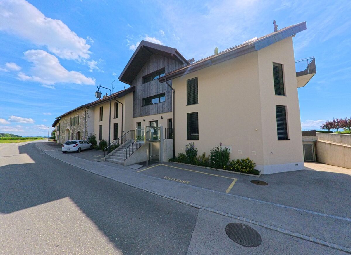 Am Ortsrand von Etoy (1163, Kanton Waadt) stehen modern renovierte Wohnhäuser mit grossen Fenstern und einer angrenzenden Strasse.