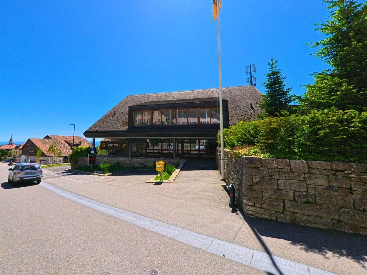 Das Gemeindehaus von Evilard (2533, Kanton Bern) steht am Rand eines kleinen Parkplatzes und ist von gepflegtem Grün umgeben.