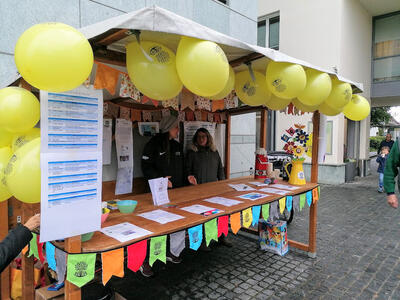 Der Familienverein Gränichen betreibt in Gränichen (5722, Kanton Aargau) einen farbig geschmückten Informationsstand mit gelben Luftballons und Veranstaltungsunterlagen.