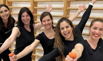 Fünf Frauen von Fast-Fit Merlischachen posieren gut gelaunt in schwarzer Sportkleidung mit kleinen Hanteln in einem Trainingsraum in Küssnacht (6403, Kanton Schwyz).