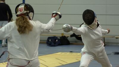 In Luzern (6006, Kanton Luzern) stehen sich zwei Fechterinnen in voller Schutzbekleidung gegenueber, waehrend sie in einer Halle mit ihren Floretts Angriffe und Paraden ausfuehren.