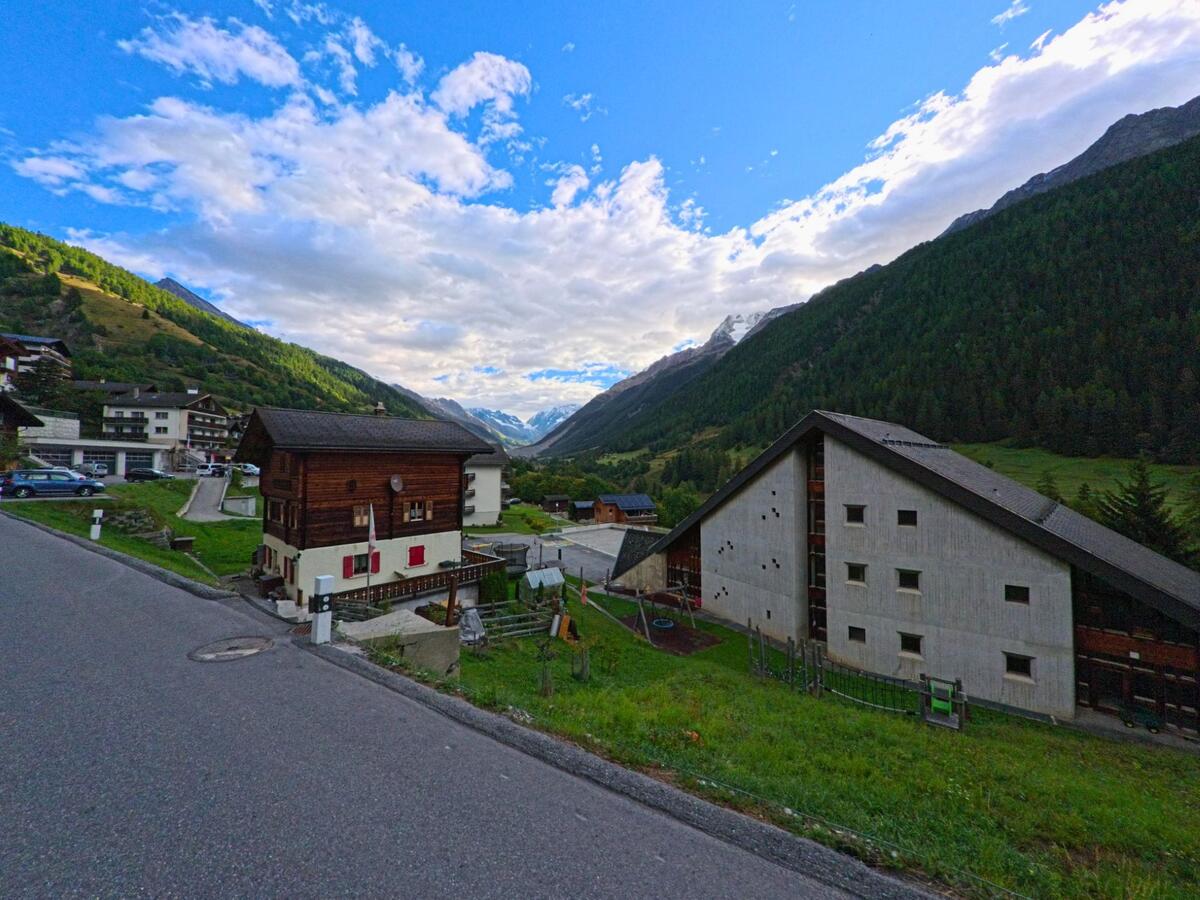 Von der Strasse in Ferden (3916, Kanton Wallis) bietet sich ein weiter Blick ins Tal mit traditionellen und modernen Gebäuden sowie den Bergen im Hintergrund.
