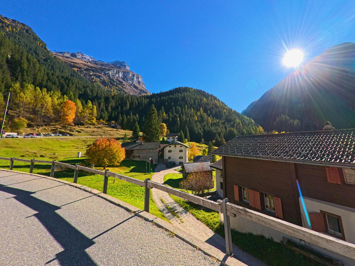Vom Geländer aus oeffnet sich der Blick auf das Dorf und die Berglandschaft von Ferrera (7444, Kanton Graubünden).