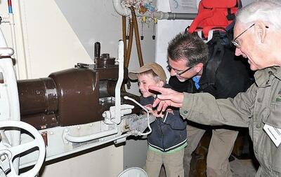Im Festungsmuseum Reuenthal in Full-Reuenthal (5324, Kanton Aargau) erklaert ein Museumsfuehrer einem Kind und seinem Vater die Bedienung einer historischen Kanone.