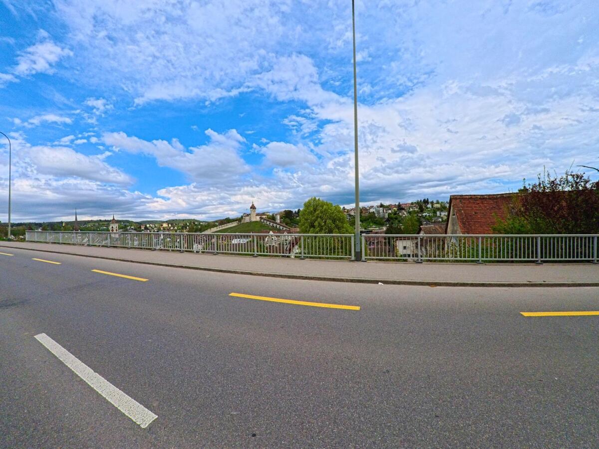  In Feuerthalen im PLZ-Gebiet 8245 im Kanton Zürich verläuft eine Strasse mit Blick auf die Altstadt von Schaffhausen, erkennbar an den markanten Kirchtürmen und der Munot-Festung.