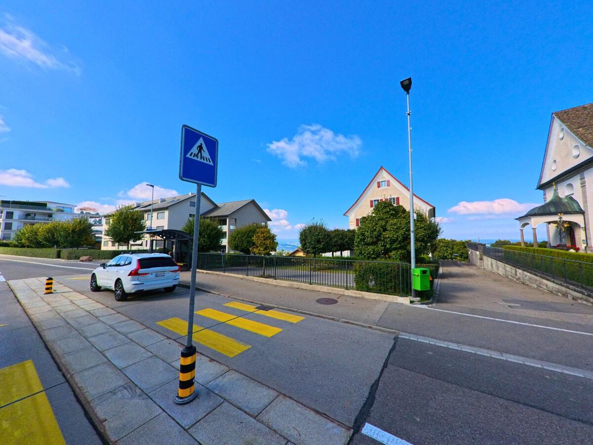 Ein Fussgängerstreifen mit Verkehrsinsel quert eine Strasse im Siedlungsgebiet von Feusisberg (8835, Kanton Schwyz).
