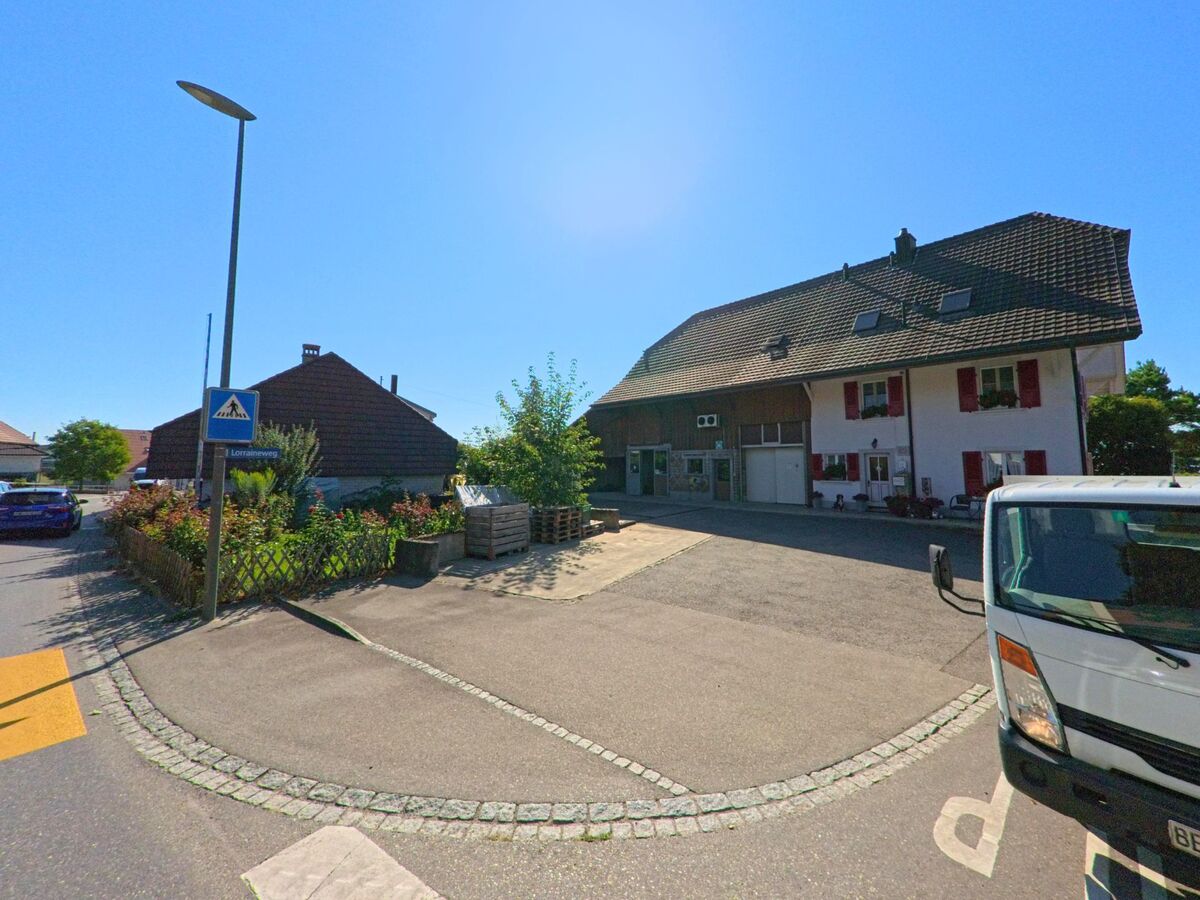 In Finsterhennen (2577, Kanton Bern) steht ein Wohnhaus mit angebauter Scheune und roten Fensterläden an einer Kreuzung mit Fussgängerstreifen.
