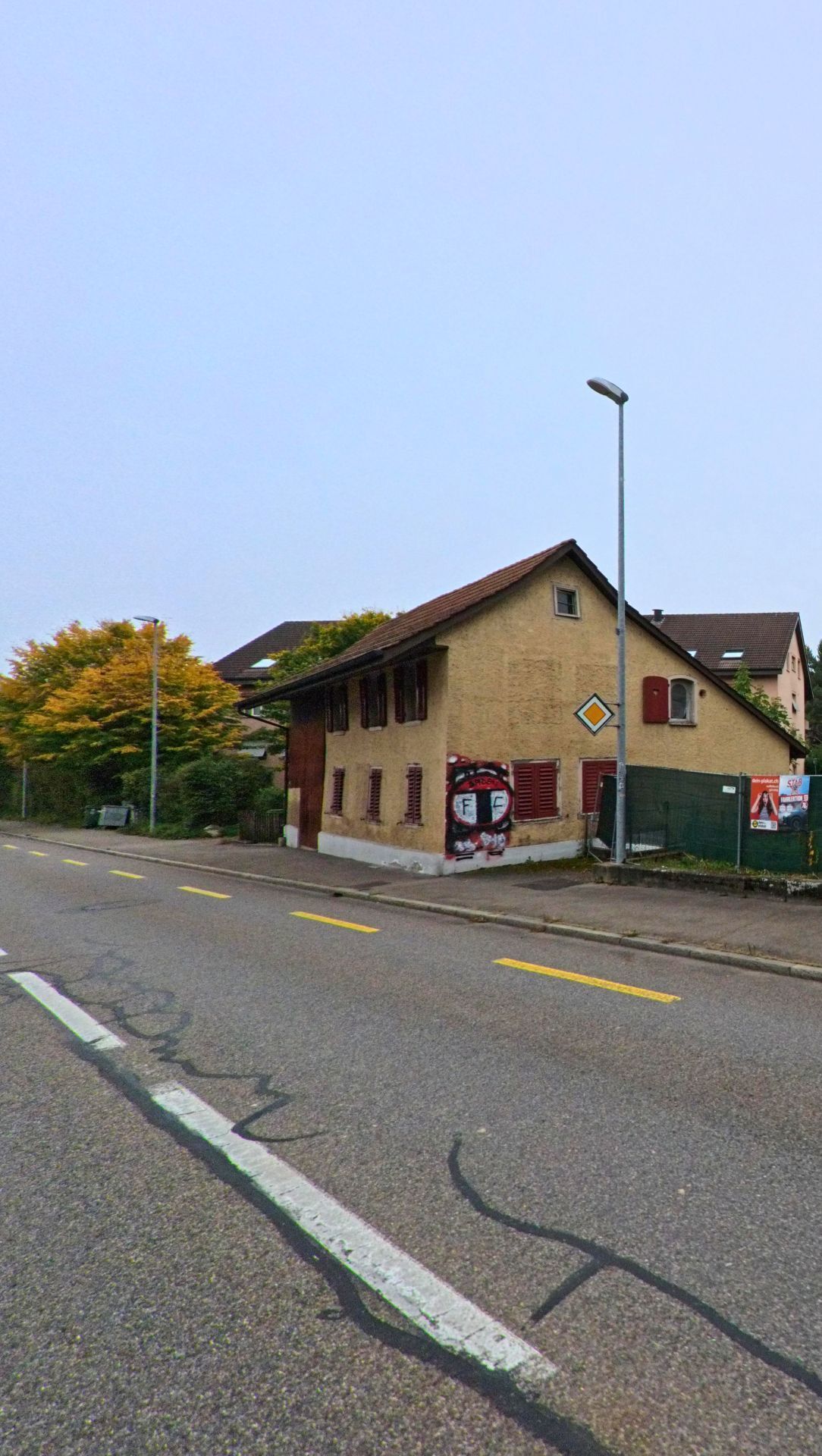 Ein älteres Wohnhaus mit rotem Fensterläden steht an einer Strasse in Fislisbach (5442, Kanton Aargau), an dessen Fassade sich ein grosses Wandgraffiti befindet.