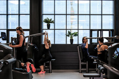 In einem Fitnessstudio in Bülach (8180, Kanton Zürich) trainieren mehrere Personen an modernen Kraftgeräten vor einer grossen Fensterfront.