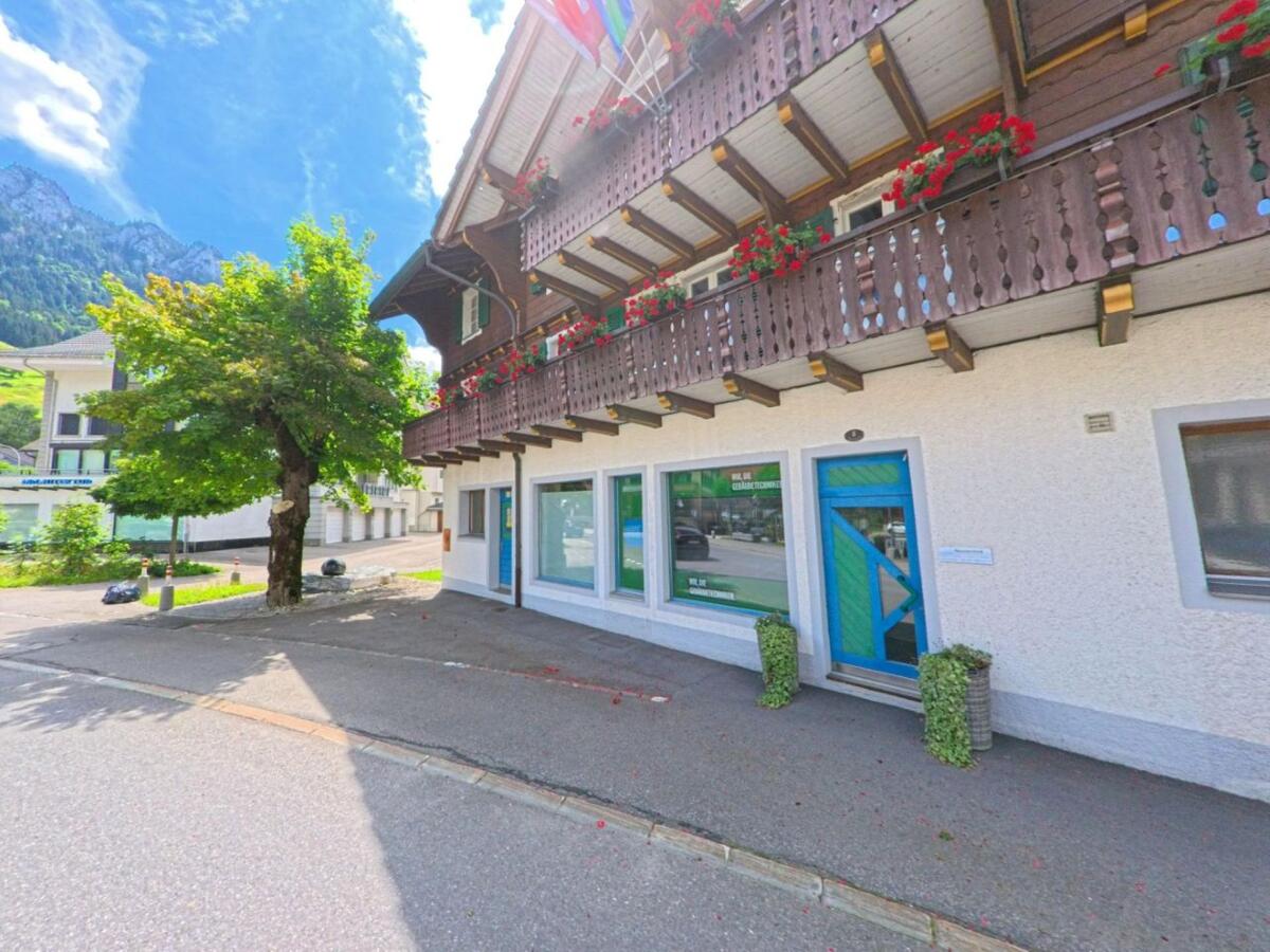 In Flühli (PLZ 6173, Kanton Luzern) zeigt sich ein typisch schweizerisches Haus mit Blumenschmuck am Holzbalkon und farbig gestalteter Eingangstür vor alpiner Kulisse.