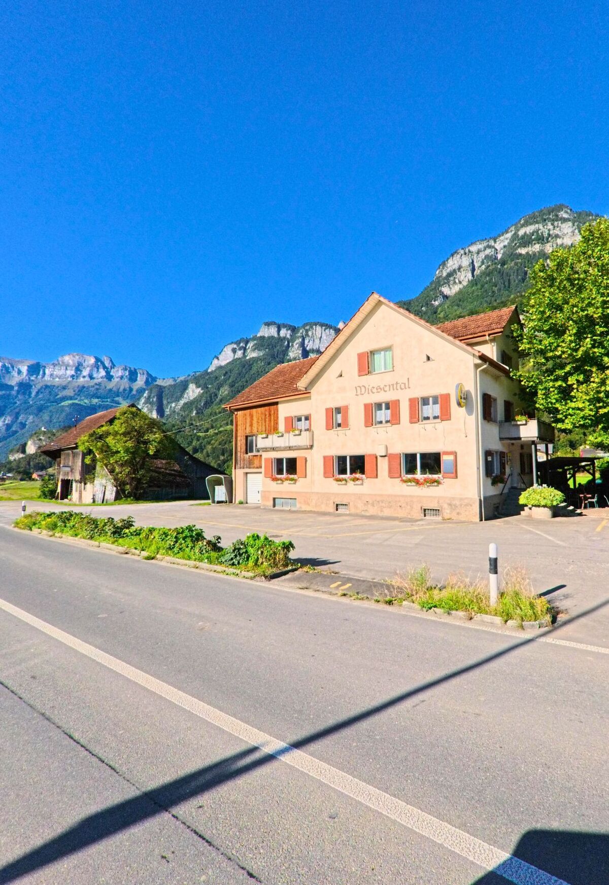 Das Gasthaus Wiesental in Flums (8893, Kanton St. Gallen) liegt am Strassenrand mit Blick auf die steilen Felswaende der umgebenden Berge.