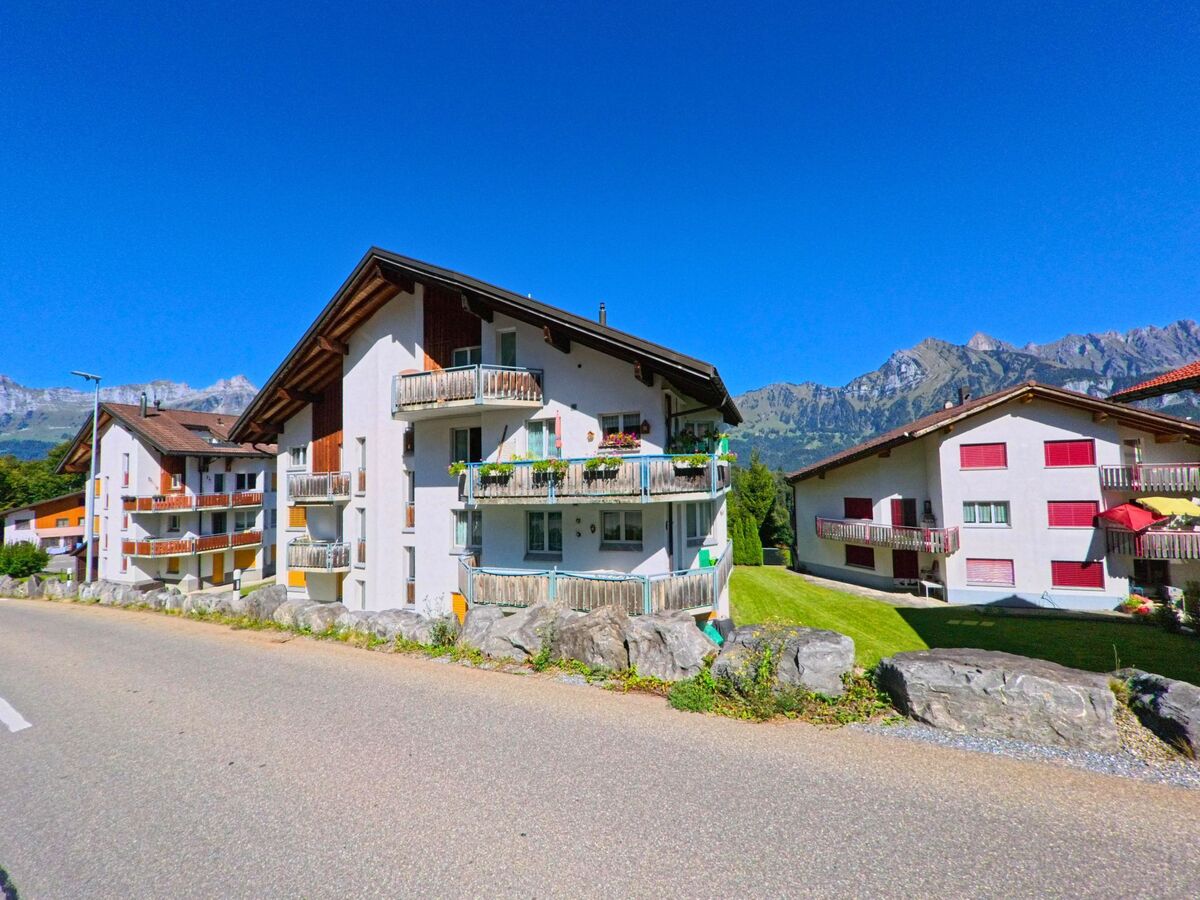 Mehrfamilienhaeuser in Flums (8896, Kanton St. Gallen) stehen entlang einer ruhigen Strasse mit Blick auf die umliegenden Berge und die Churfirsten.
