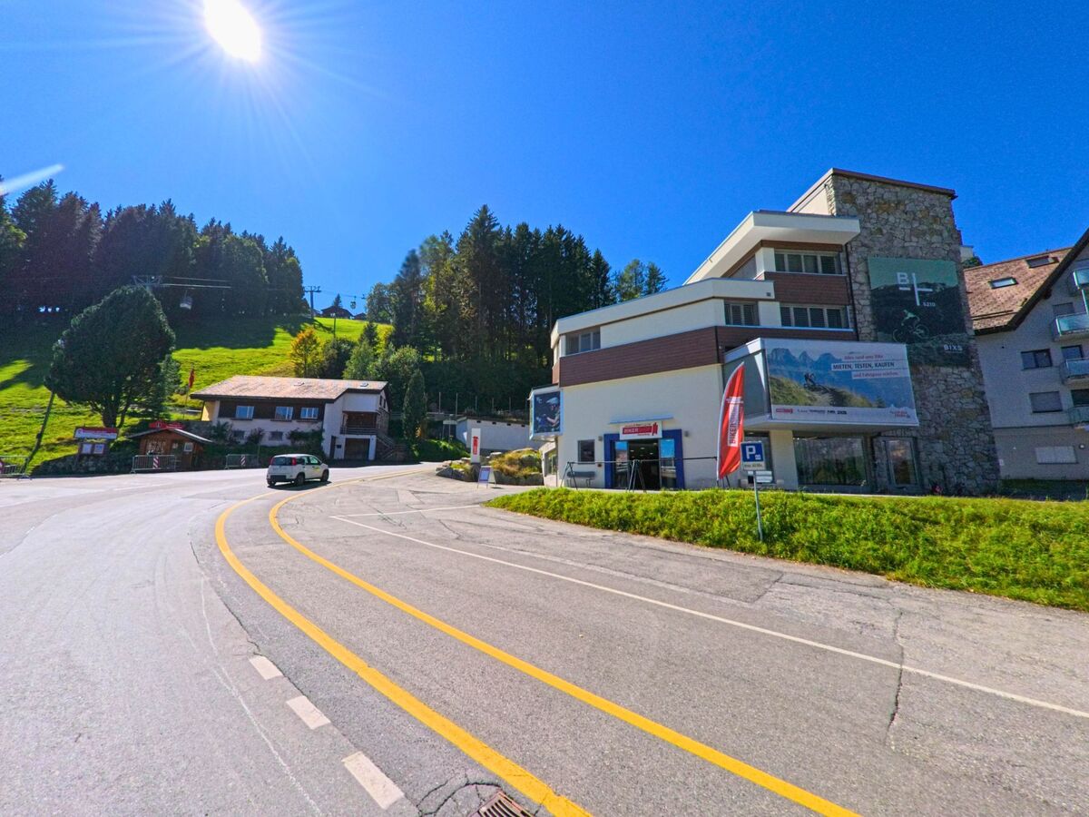 Bei strahlendem Sonnenschein liegt in Flums (8897, Kanton St. Gallen) die Talstation der Bergbahnen Flumserberg an der Strasse mit Blick auf die gruene Skipiste.