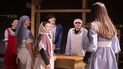 Junge Darstellerinnen des Fördervereins Kinder & Jugendtheater Kunterbunt in Schneisingen (5425, Kanton Aargau) stehen in Kostümen auf der Bühne während einer Probe.