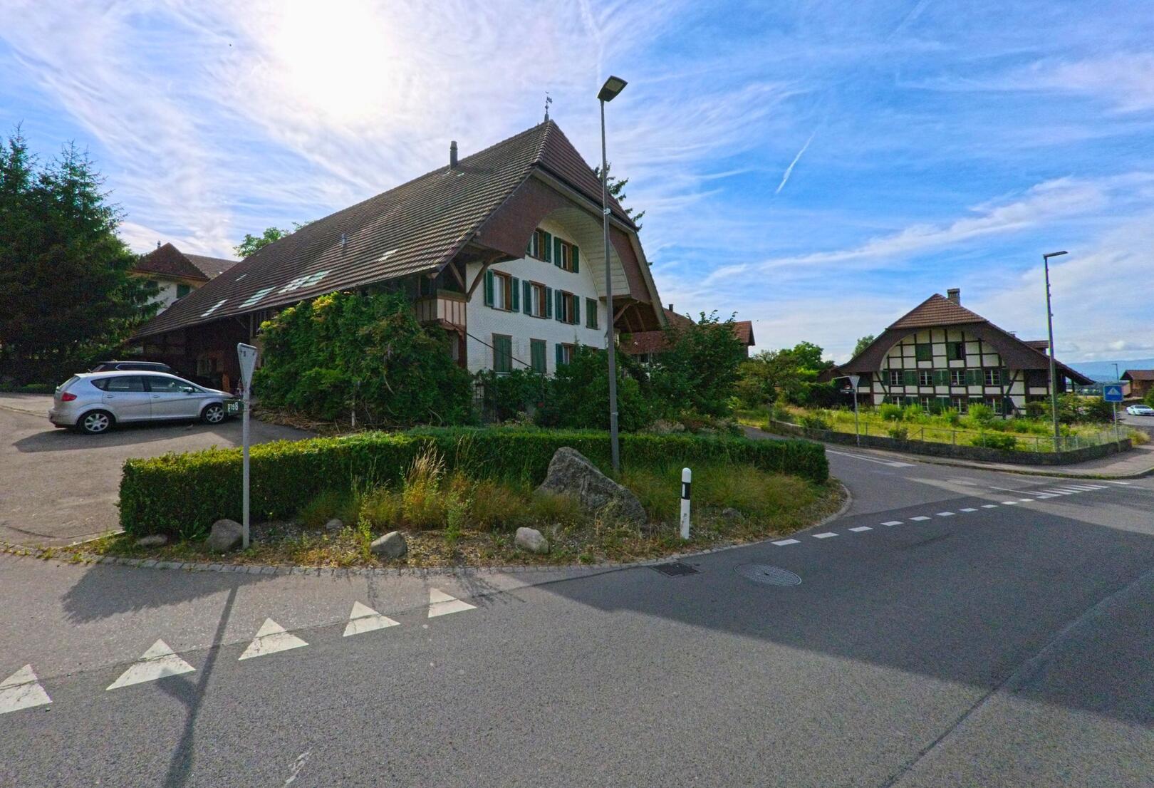 In Fräschels (3284, Kanton Bern) prägen traditionelle Bauernhäuser mit markanten Giebeldächern und grünen Fensterläden das Dorfbild an einer ruhig gelegenen Kreuzung.