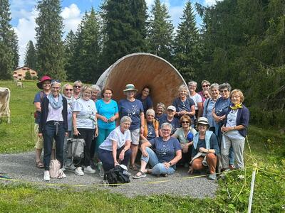 Vor einer grossen Holzinstallation posiert der Frauenchor Richterswil in Richterswil (8805, Kanton Zürich) bei einem Ausflug in einheitlichen Vereinshemden.